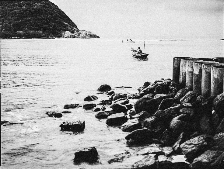 a boat floating in the water near rocks and seawall