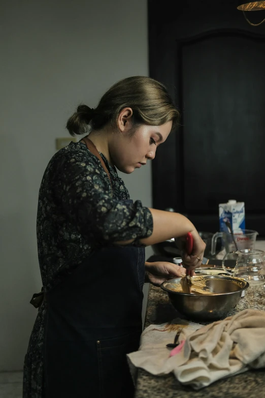 a woman standing at the kitchen counter making food