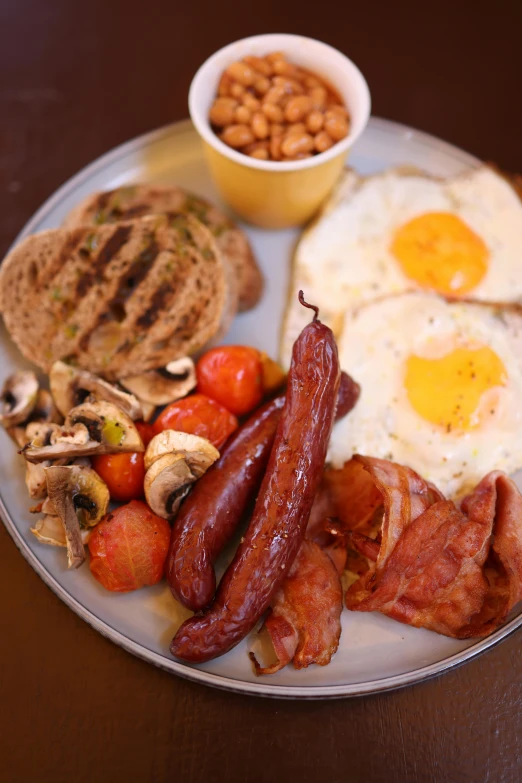 a plate with sausage, beans, eggs, and bacon on it