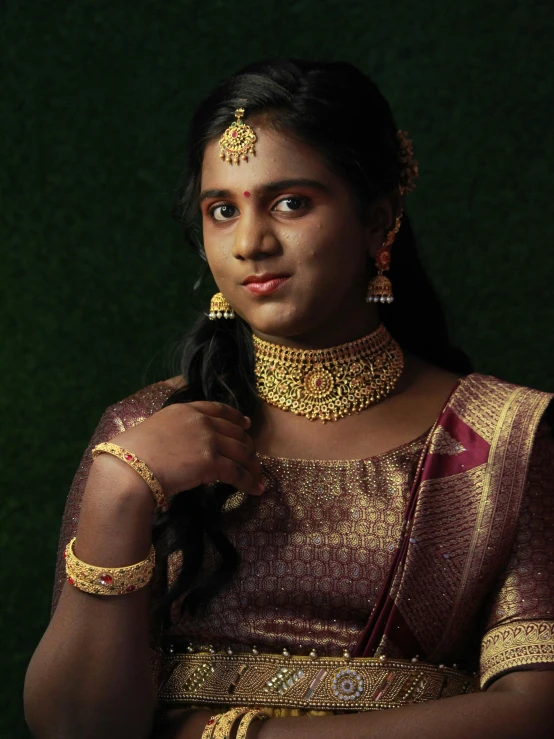 a woman with dark skin wearing a golden outfit and jewelry