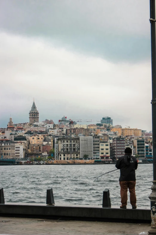 two people fishing with the background of a city in the distance