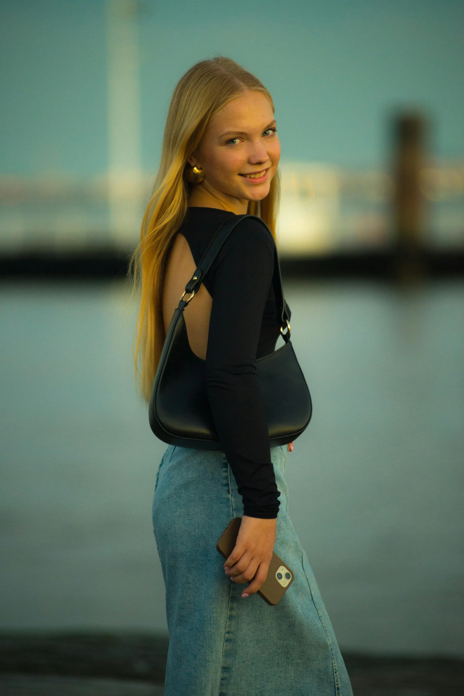 a woman wearing jeans is standing in front of a body of water