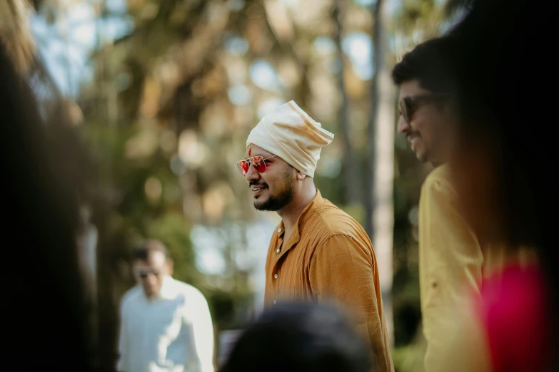 the man in a turban smiles as he stands next to other people