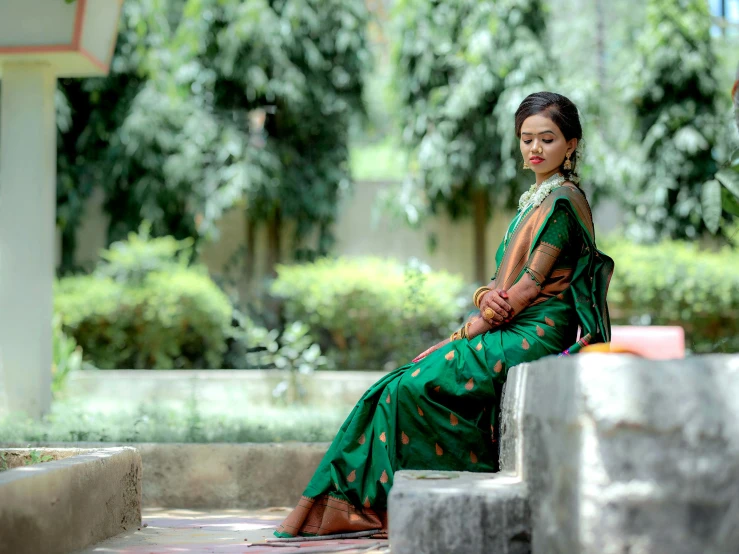 woman wearing a green dress is sitting on steps