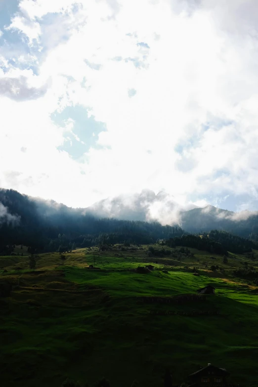 an airplane flying in a cloudy sky above a lush green mountain valley