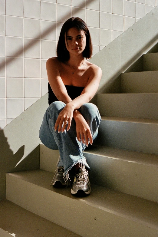 a girl sits on a staircase near a hand rail