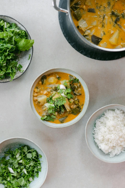 three bowls of soup next to a pot of rice