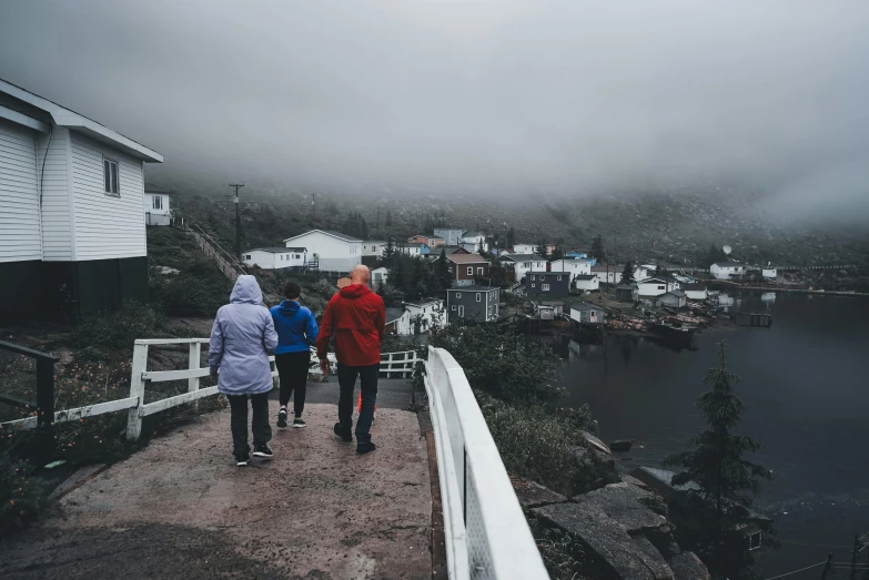 three people walking up a walkway towards a neighborhood