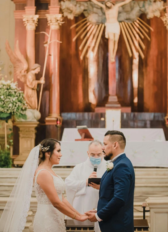 bride and groom in white at the alter during the wedding ceremony