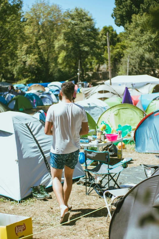 a person with shorts walking among many tents