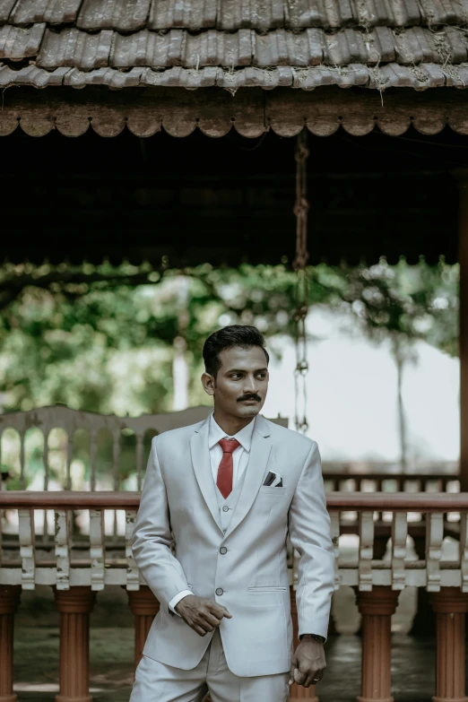 a young man in a white suit, standing in a room