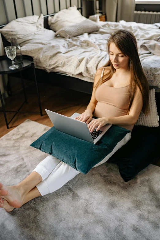 a woman sitting on the floor with a laptop