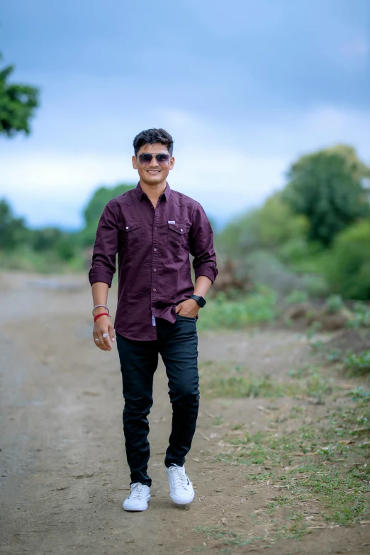 man with purple shirt and sunglasses walking down dirt road