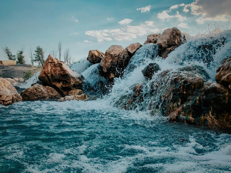 a waterfall pouring into a lake surrounded by rocks