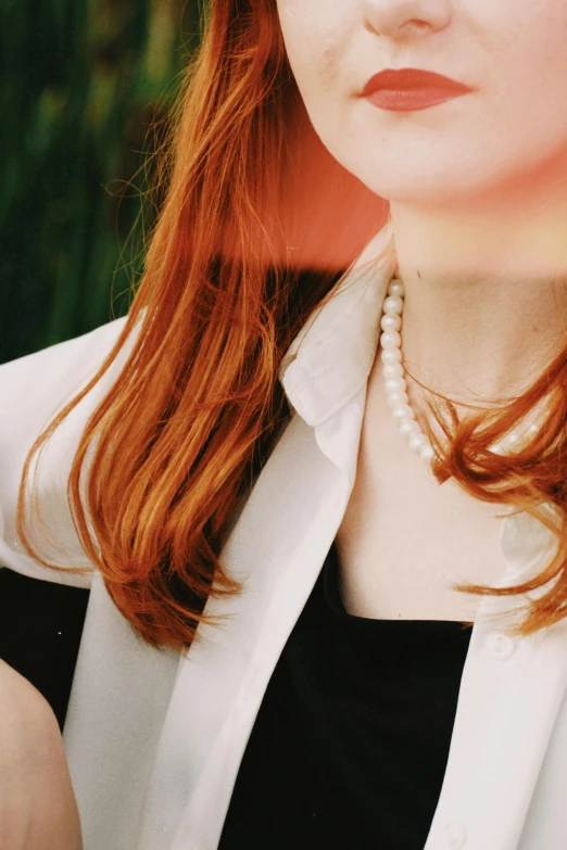 a red haired woman wearing a white shirt and pearls necklace