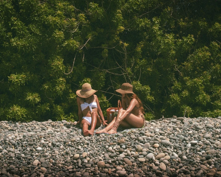 three people sitting on rocks next to a forest