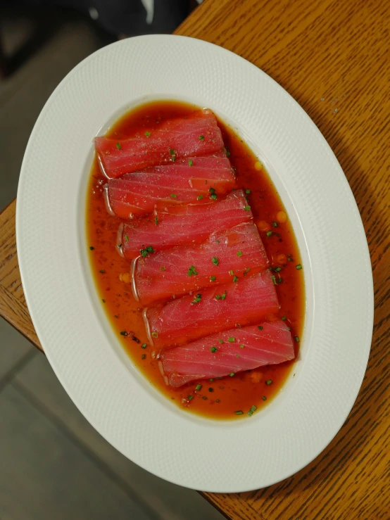 slices of tuna with sauce and herbs in a plate