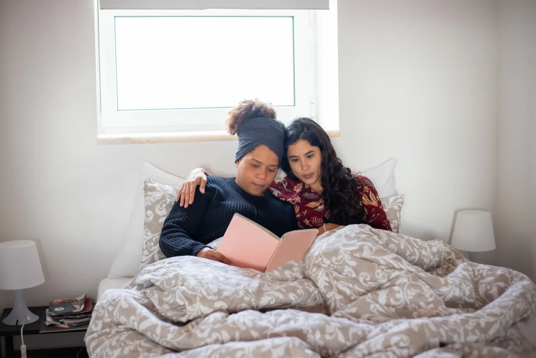 two women are in bed with an unmade book