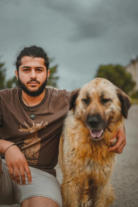 a man sits beside his dog on a cloudy day