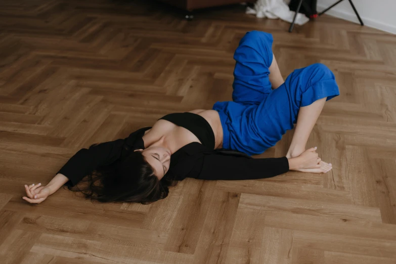 a girl in blue is laying on a wooden floor