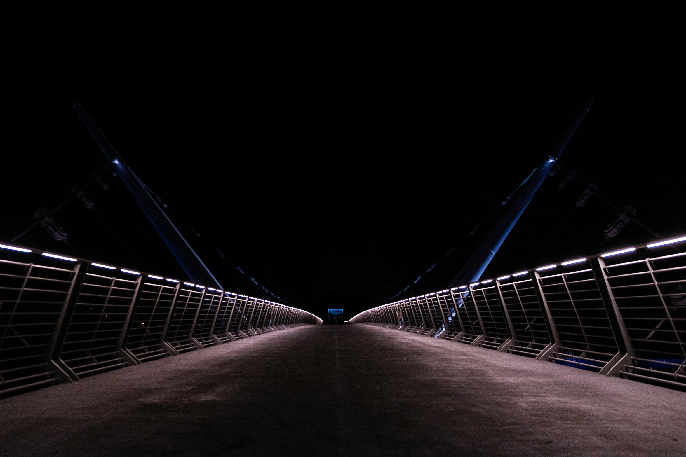 a long sidewalk with an illuminated walkway that goes down