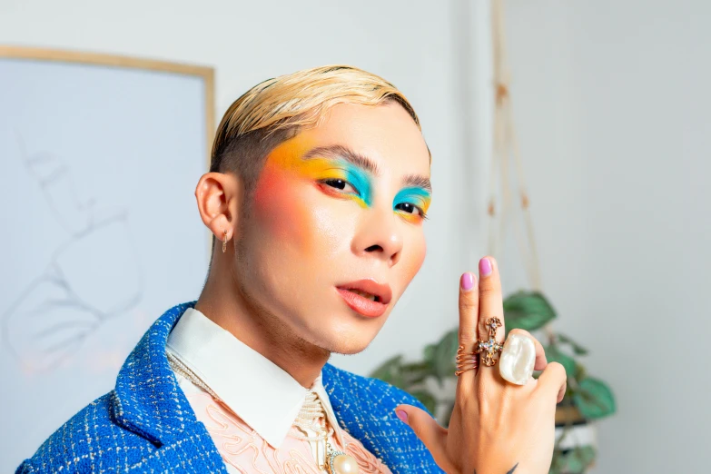 the model is wearing bright makeup and blue jacket