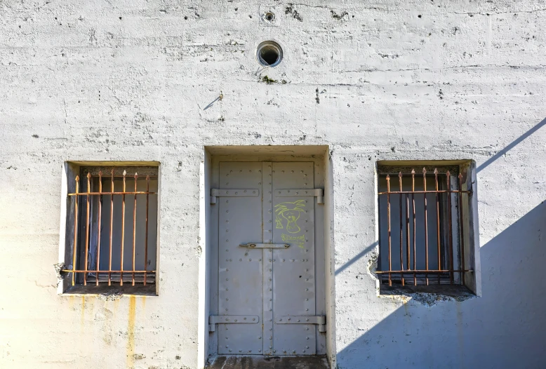 a concrete building with two windows next to a doorway