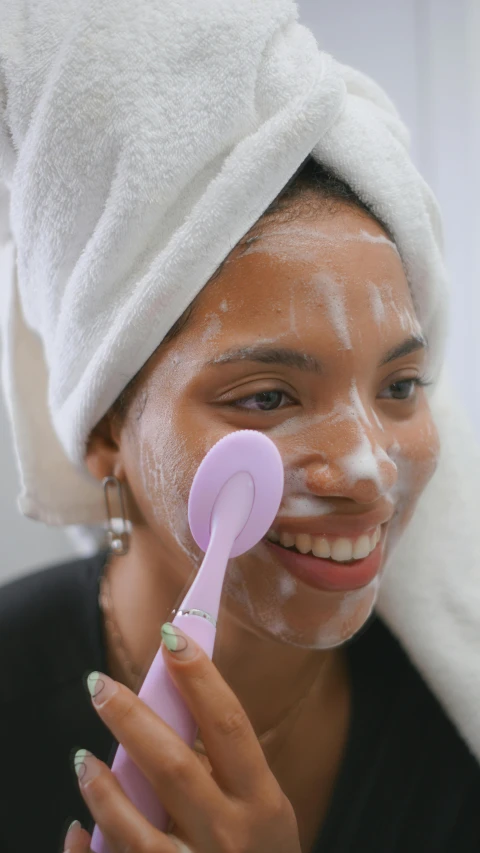 a woman wearing a towel holding a pink toothbrush