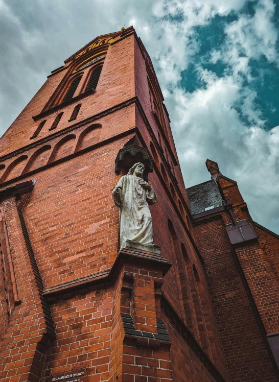 a po taken from below looking up at an old brick building with a statue in the middle