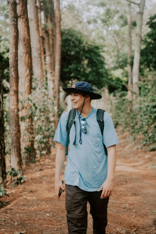 a man walks down a path wearing a hat and backpack