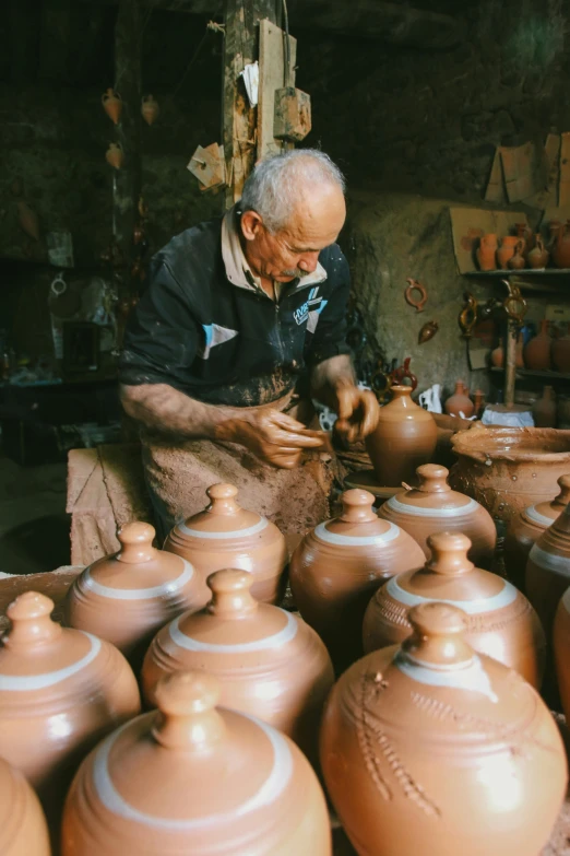 an old man working on clay pots in a pottery shop