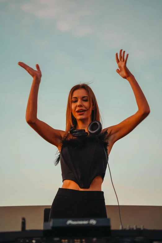 a woman with her arms in the air with headphones on her ears