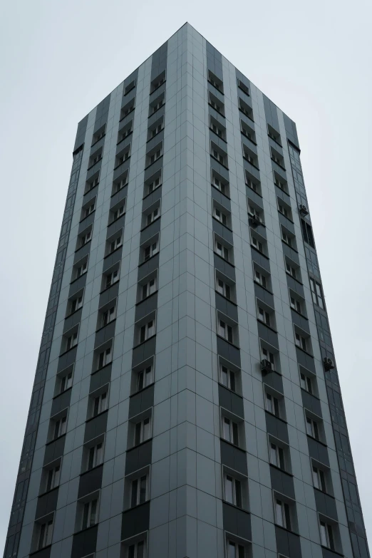 a tall tower building is standing against a gray sky