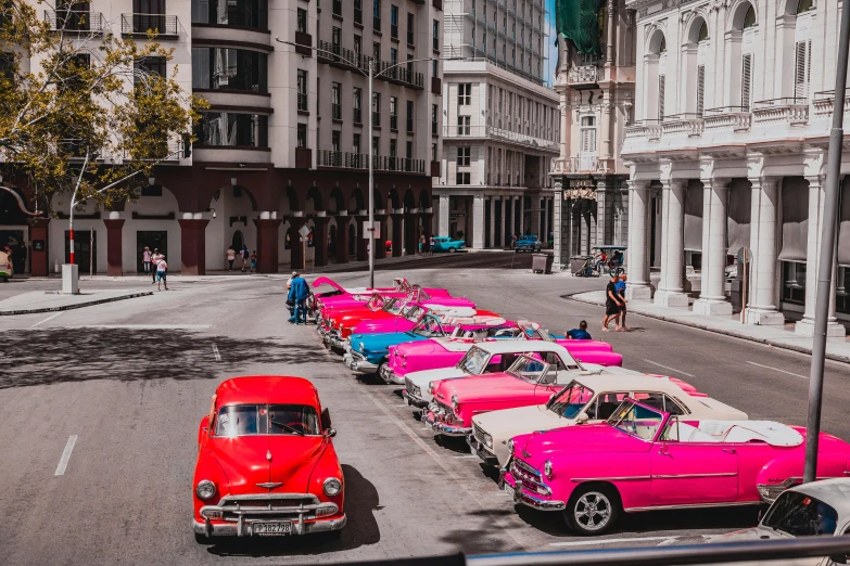 a street filled with parked pink and white cars