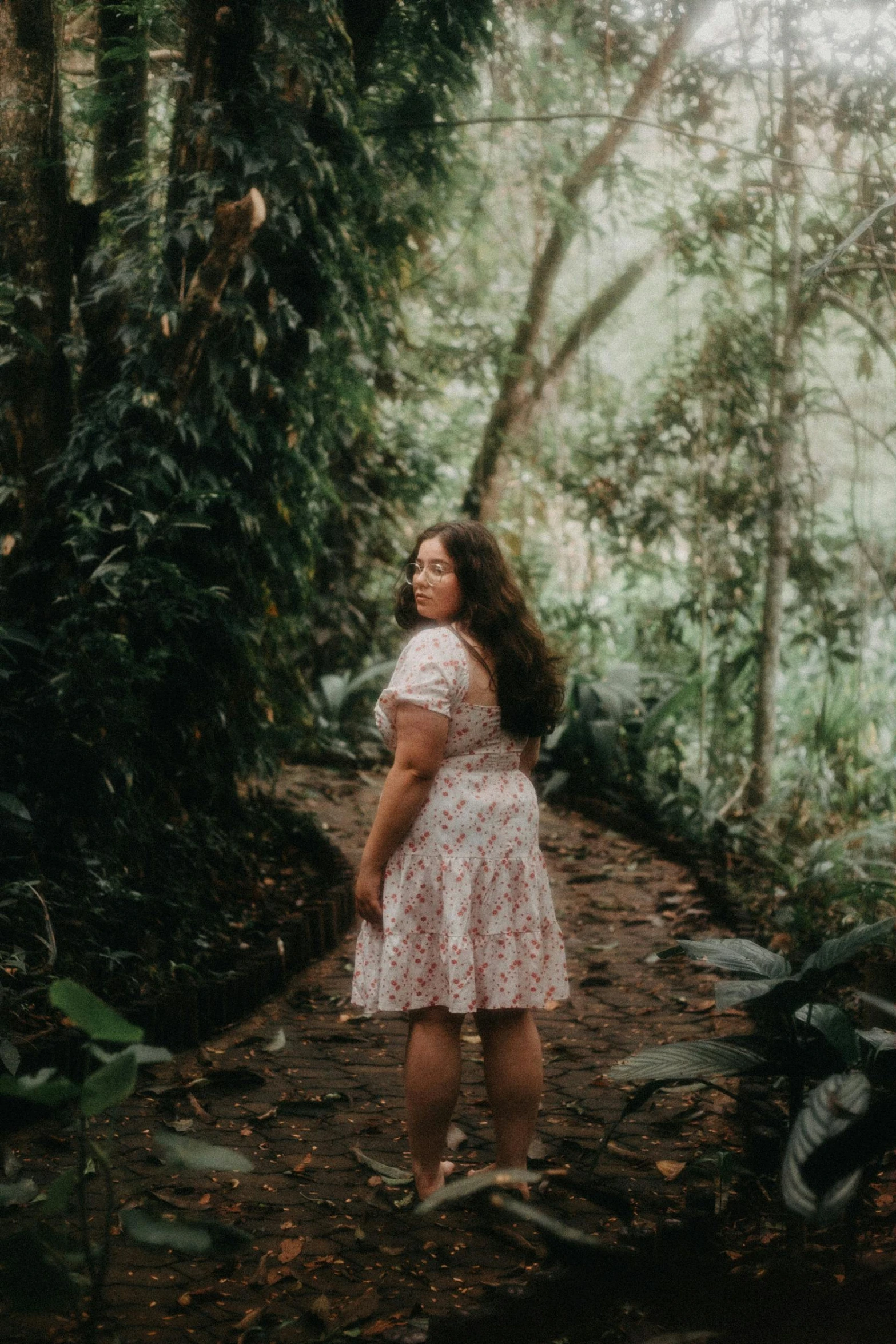 the woman stands in front of a forest with trees