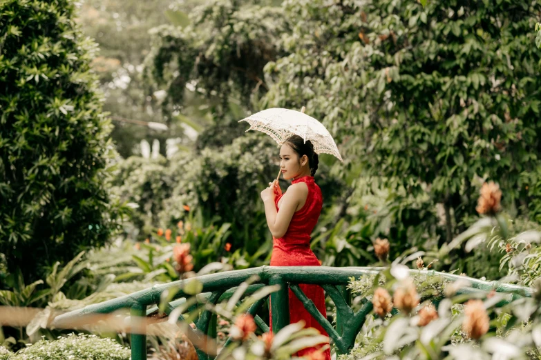 woman in red standing on a bridge holding an umbrella