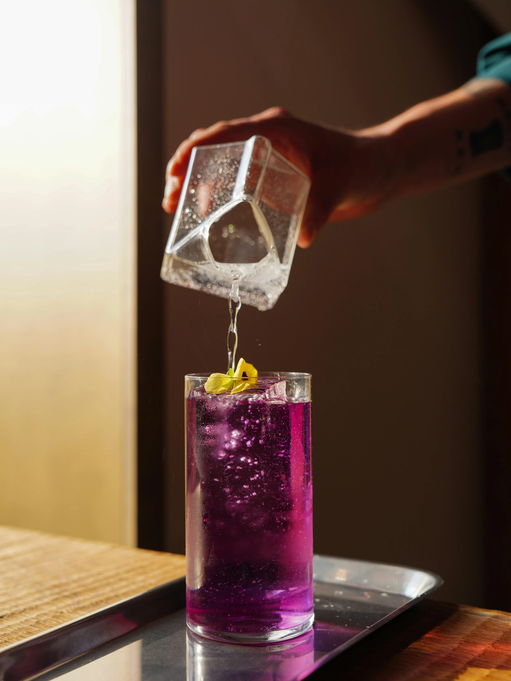 a person adding lemon wedges to a purple drink