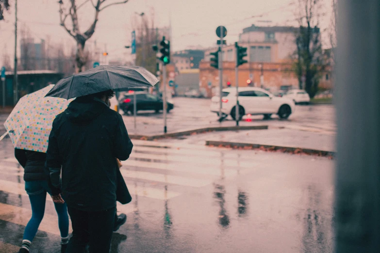 people walking on the street holding umbrellas in the rain