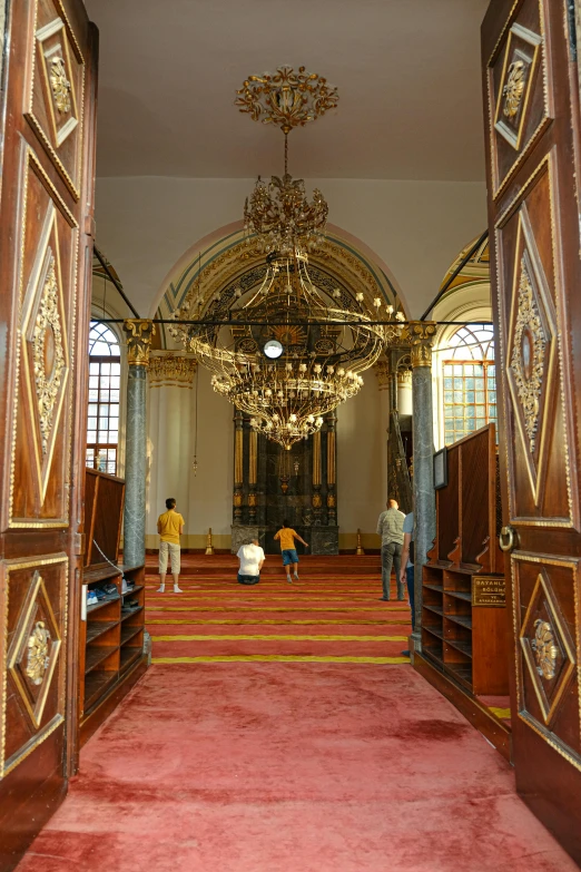 some people in a room with a chandelier and some stairs