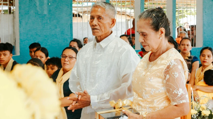 a bride and groom in wedding attire are being greeted by a family member