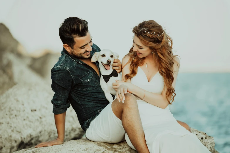 a couple sits on the edge of a cliff with their dog