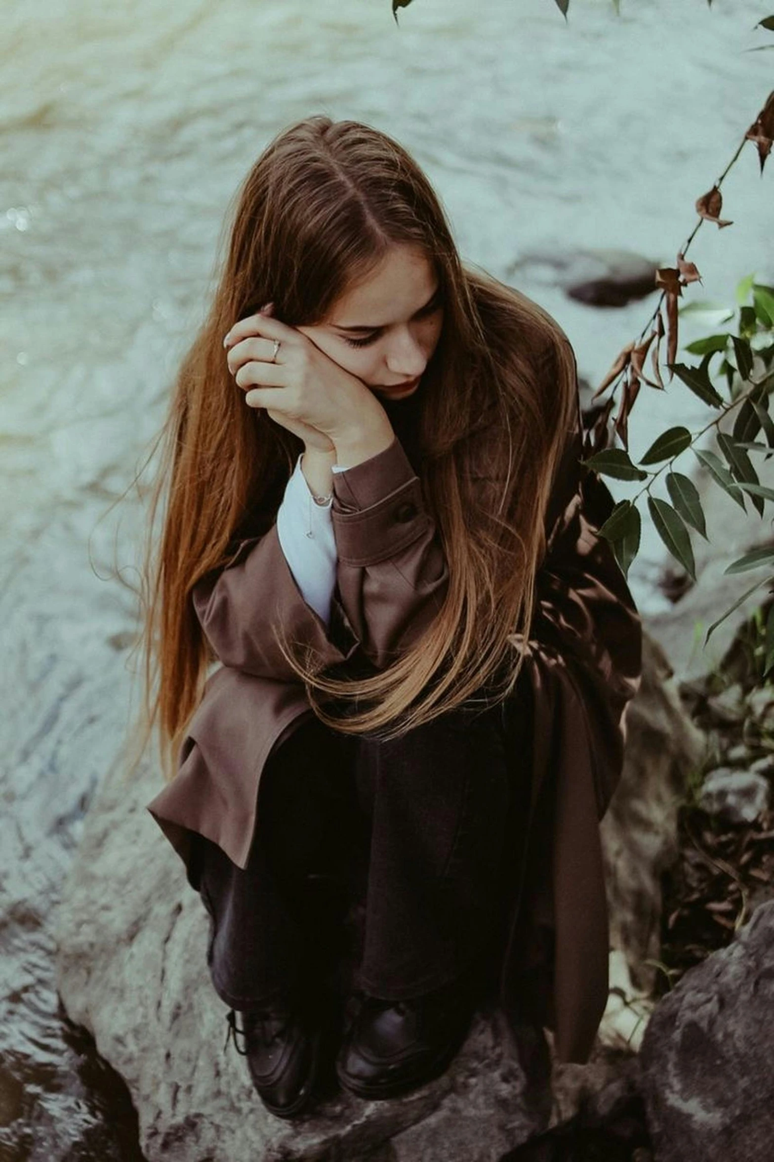 a woman sitting on some rocks next to a river