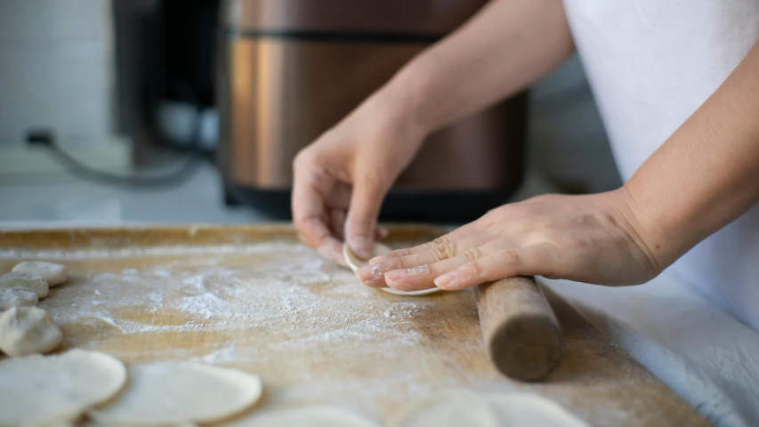 a woman kneading dough on top of a wooden table