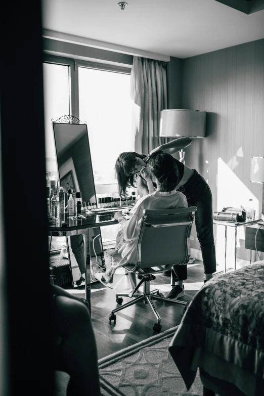 two women in a bedroom standing by a chair