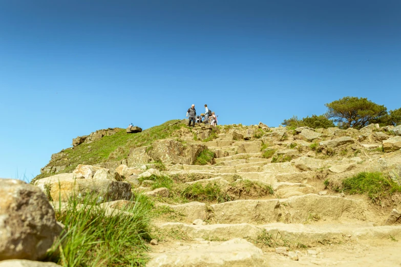 a group of people standing on top of a rock covered hillside