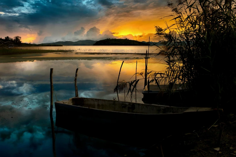 a boat is sitting next to the water in the sunset