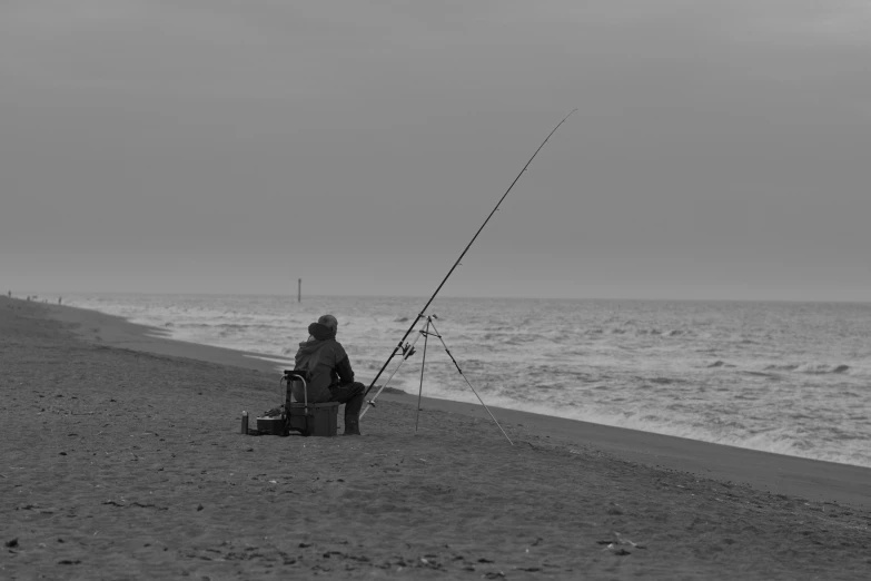 black and white po of a man fishing at the ocean