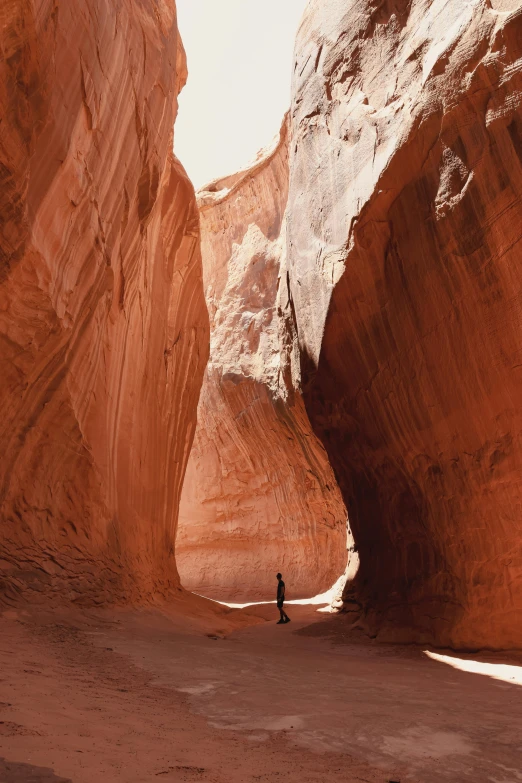 a man walking through a canyon near a rock wall