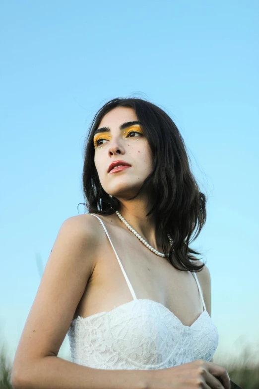 a woman is wearing a white dress and gold makeup