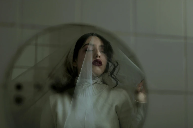 a woman wearing a veil stares in a mirror